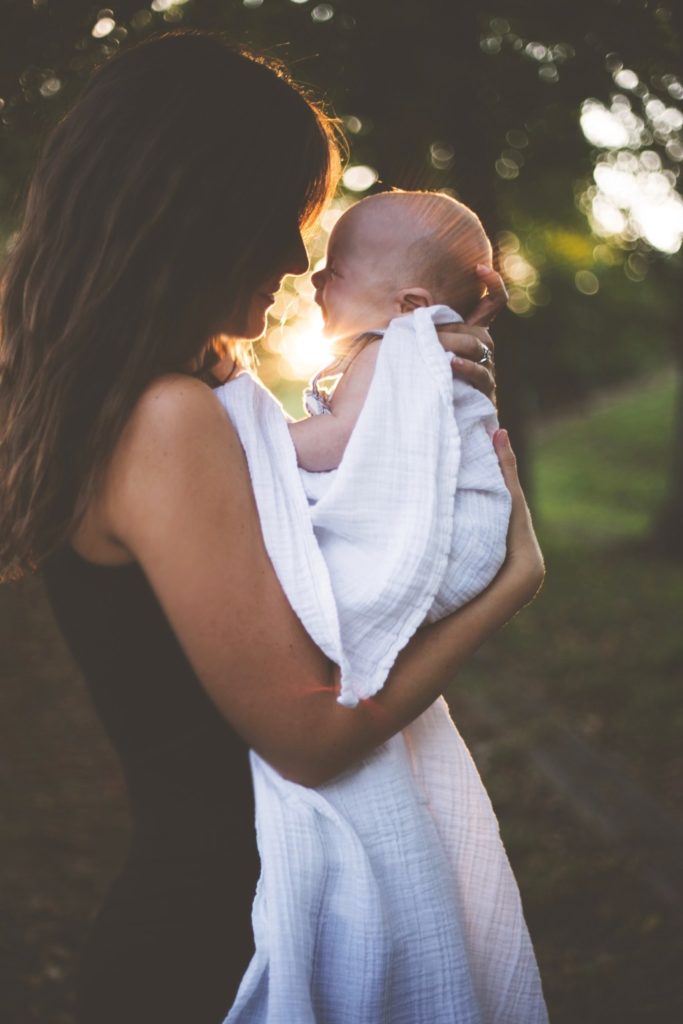 mother with infant baby swaddle