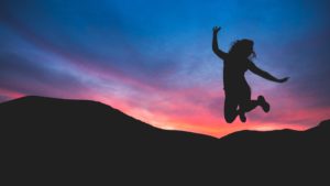 woman jumping with a blue and pink sky backdrop