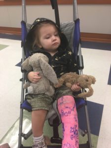 child in stroller with a pink cast on leg