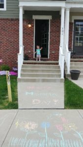 girl in front of green and brick house