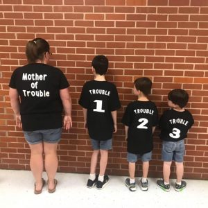 Mom and three sons showing off black t-shirts. Mother of Trouble, Trouble 1, Trouble 2, Trouble 3