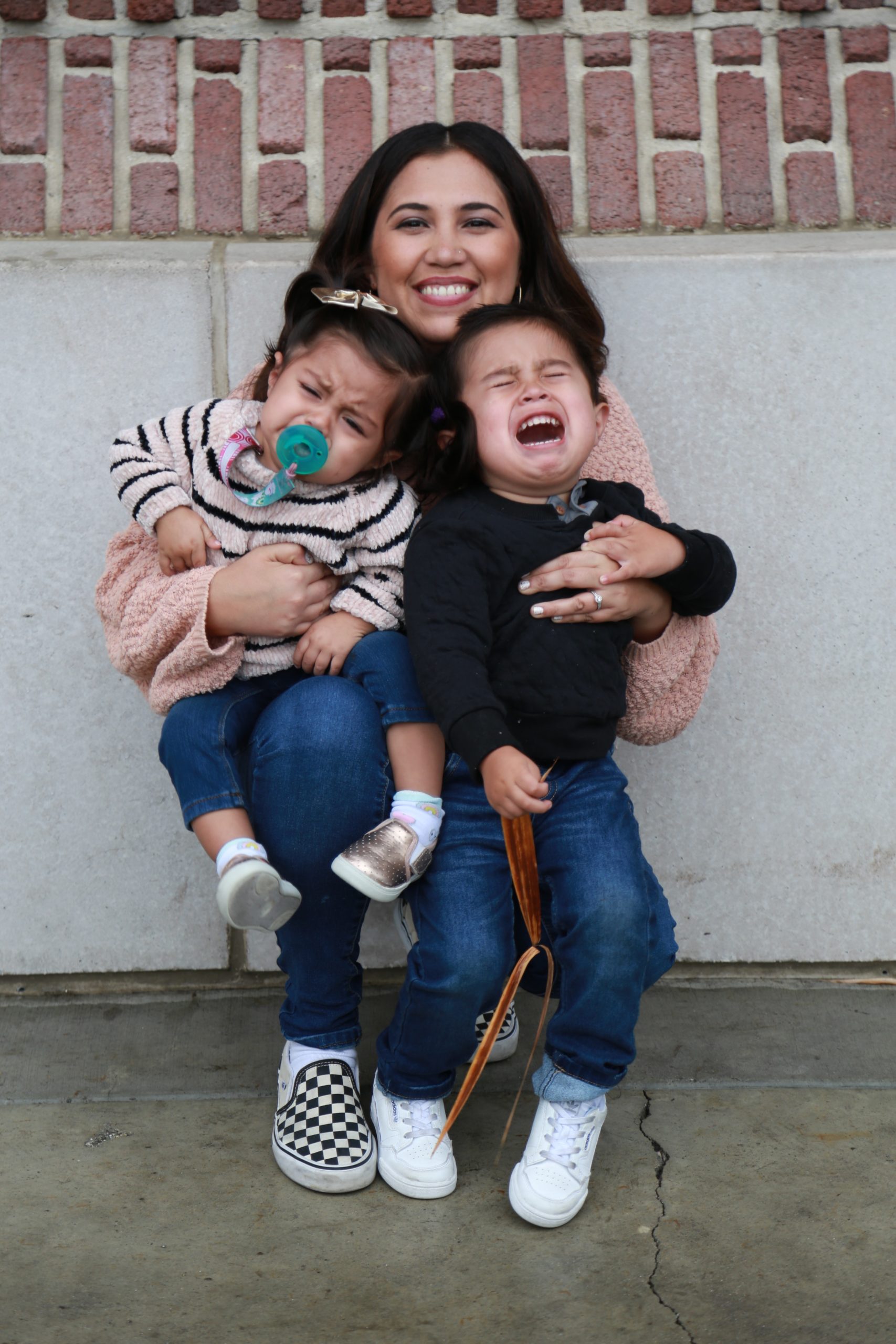 mother hugging toddlers throwing a tantrum