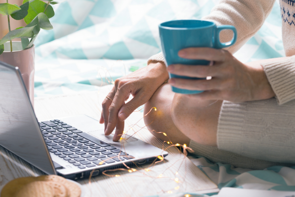 Woman holding coffee working on a laptop