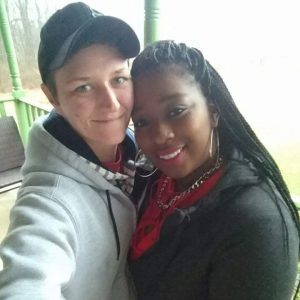 Two women in a bi-racial relationship holding each other and smiling 