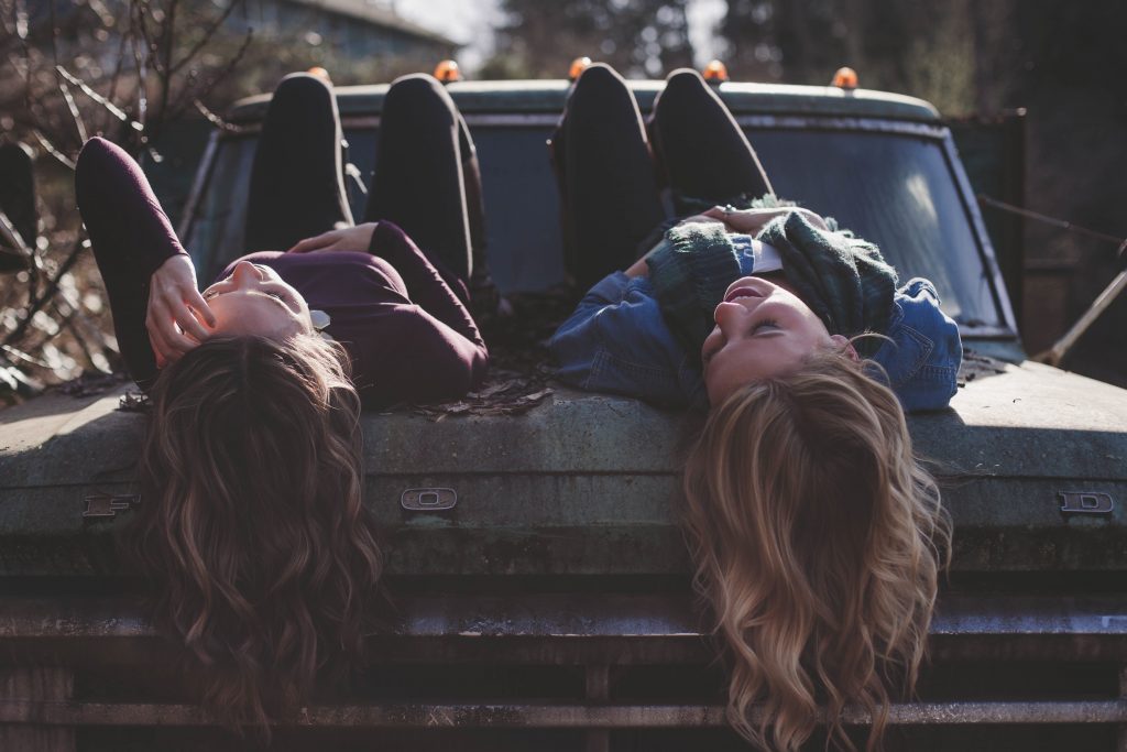 two women hanging off front of truck