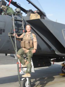 Woman in uniform standing on ladder in front of military jet