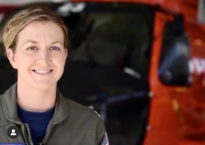 Woman standing in front of military helicopter smiling