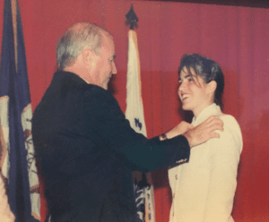 A woman in military uniform getting pinned with her pilot wings at a ceremony