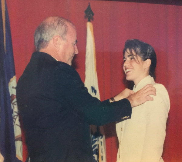 A woman in military uniform getting pinned with her pilot wings at a ceremony