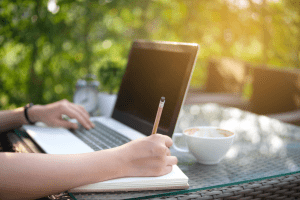woman writing at table outside
