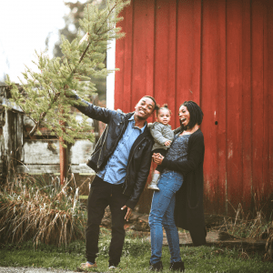 Man, Woman, and toddler smiling with real Christmas Tree on a farm