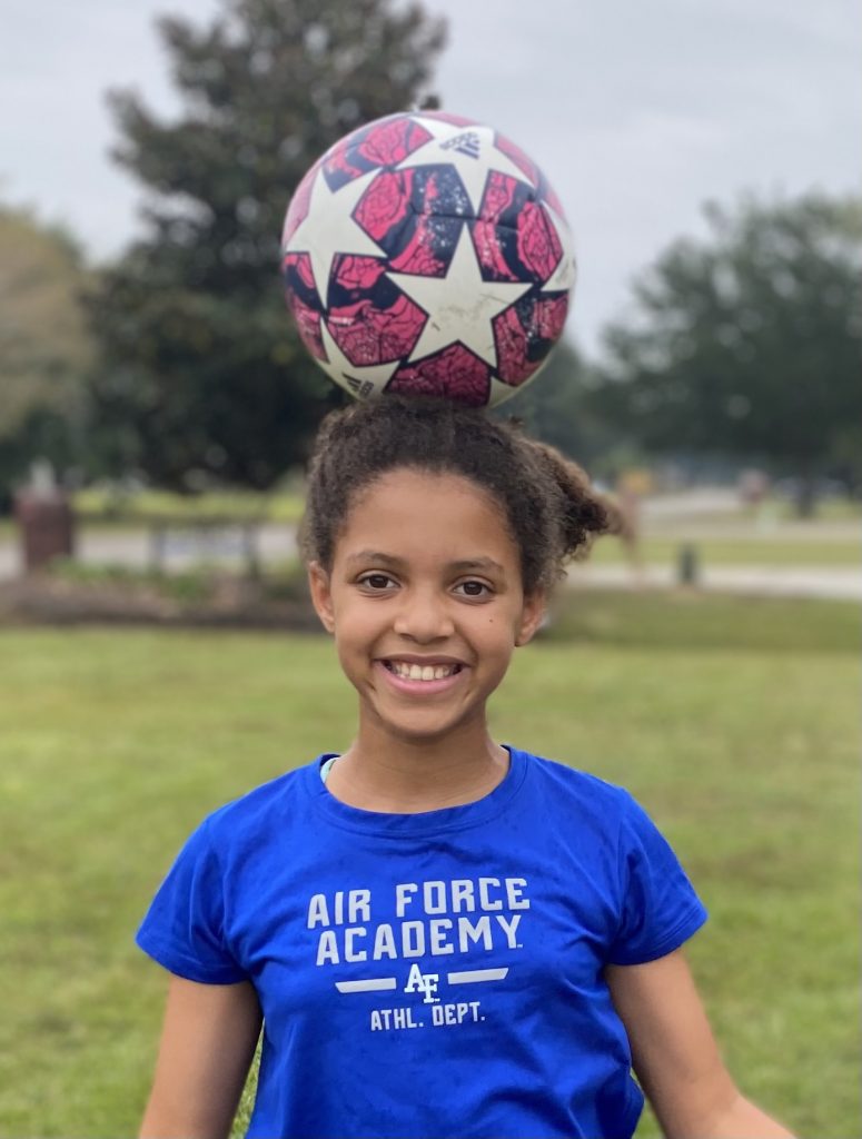 girl with soccer ball balanced on head