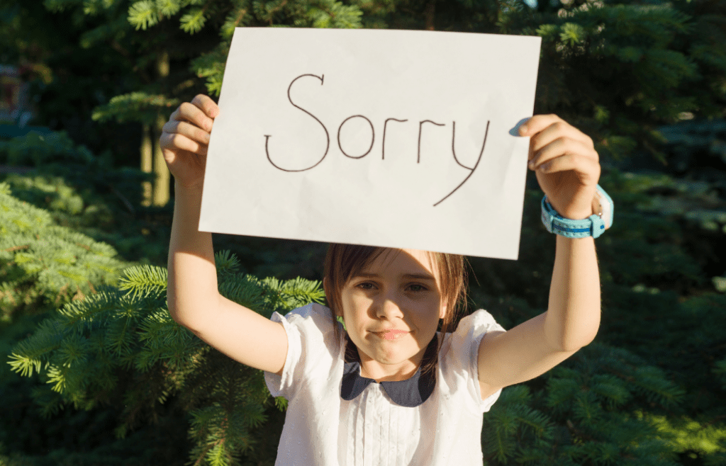 girl holding up a sign with "sorry"