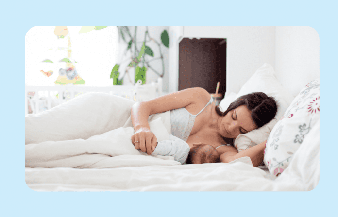 woman breastfeeding in bed on light blue background