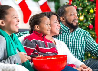 A family laughing while watching a movie together at the holidays