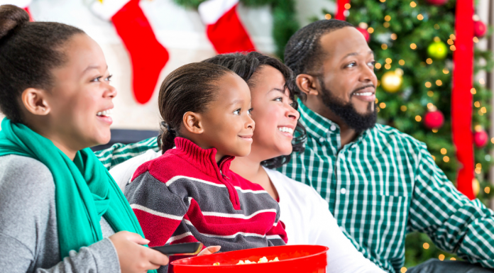 A family laughing while watching a movie together at the holidays