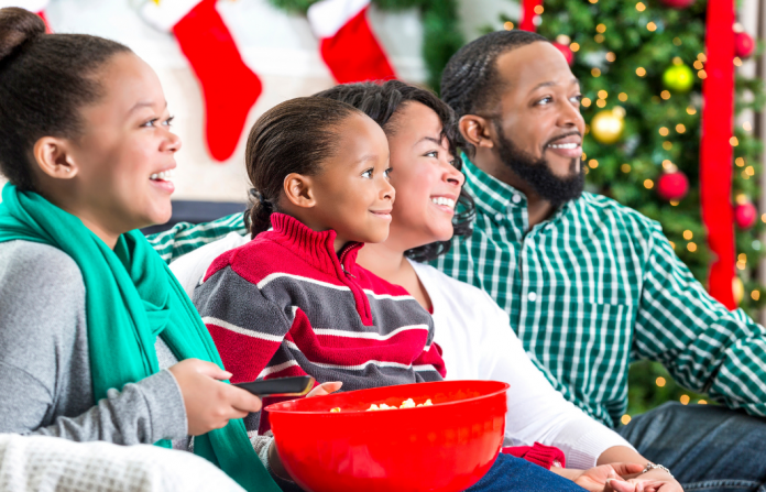 A family laughing while watching a movie together at the holidays