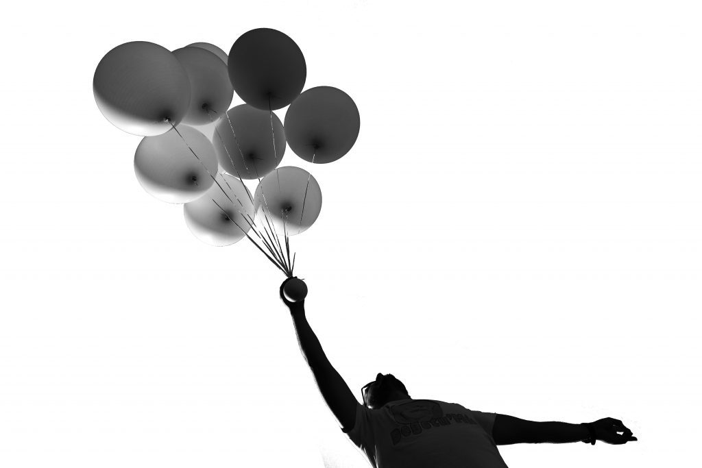 man holding balloons in black and white