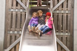 three kids on a slide on a playground