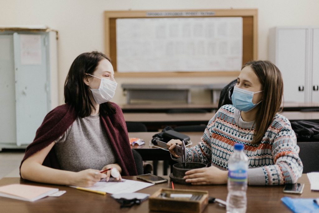 two college students wearing masks at a desk