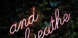 and breathe neon sign on greenery