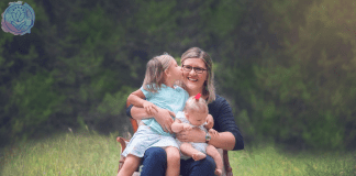 mother hugging 2 daughters on a chair in a field