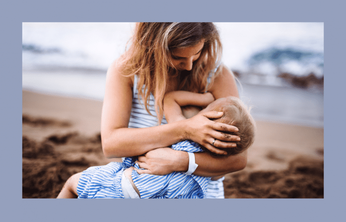 mother breastfeeding toddler on beach