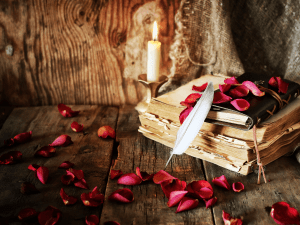 flower petals with a worn book and soft candle to indicate romance