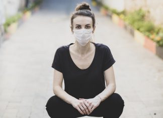 woman sitting on the ground and wearing a protective mask