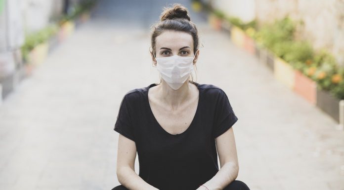 woman sitting on the ground and wearing a protective mask