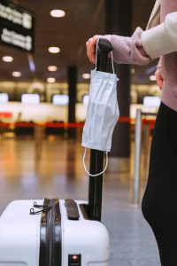 person with suitcase and mask in airport traveling