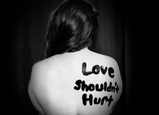 woman with "love shouldn't hurt" on back