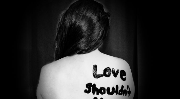 woman with "love shouldn't hurt" on back