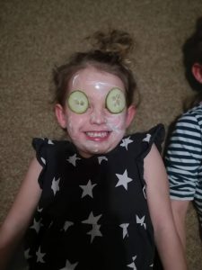 young girl with face mask and cucumbers on eyes