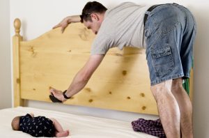 baby on bed with dad taking a picture over it