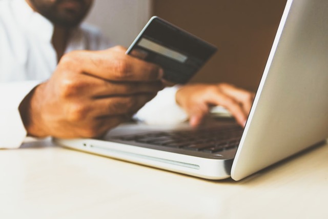 person on computer holding a credit card