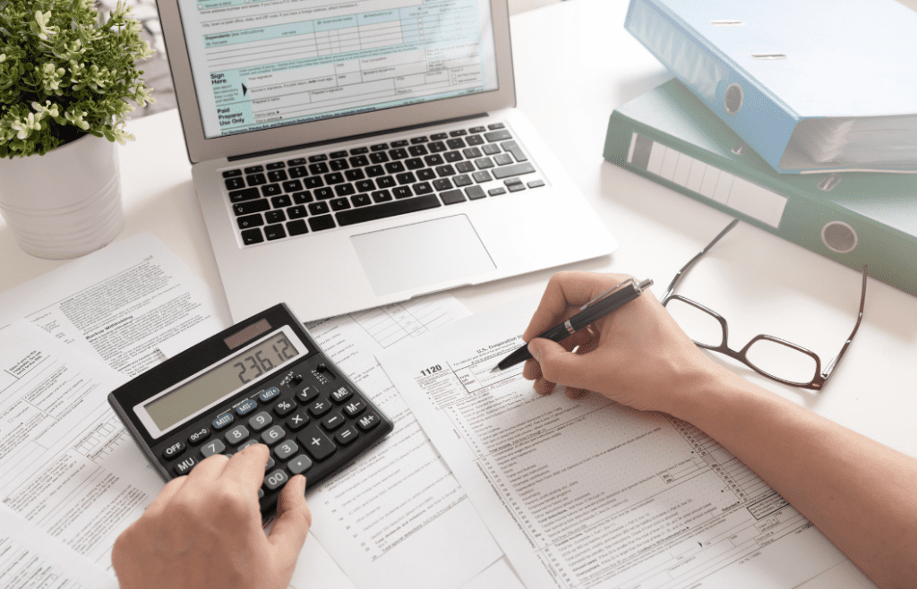 person with papers, computer, and calculator working on taxes