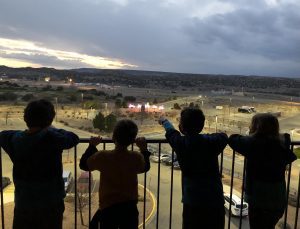 four children standing on a balcony watching the sunset