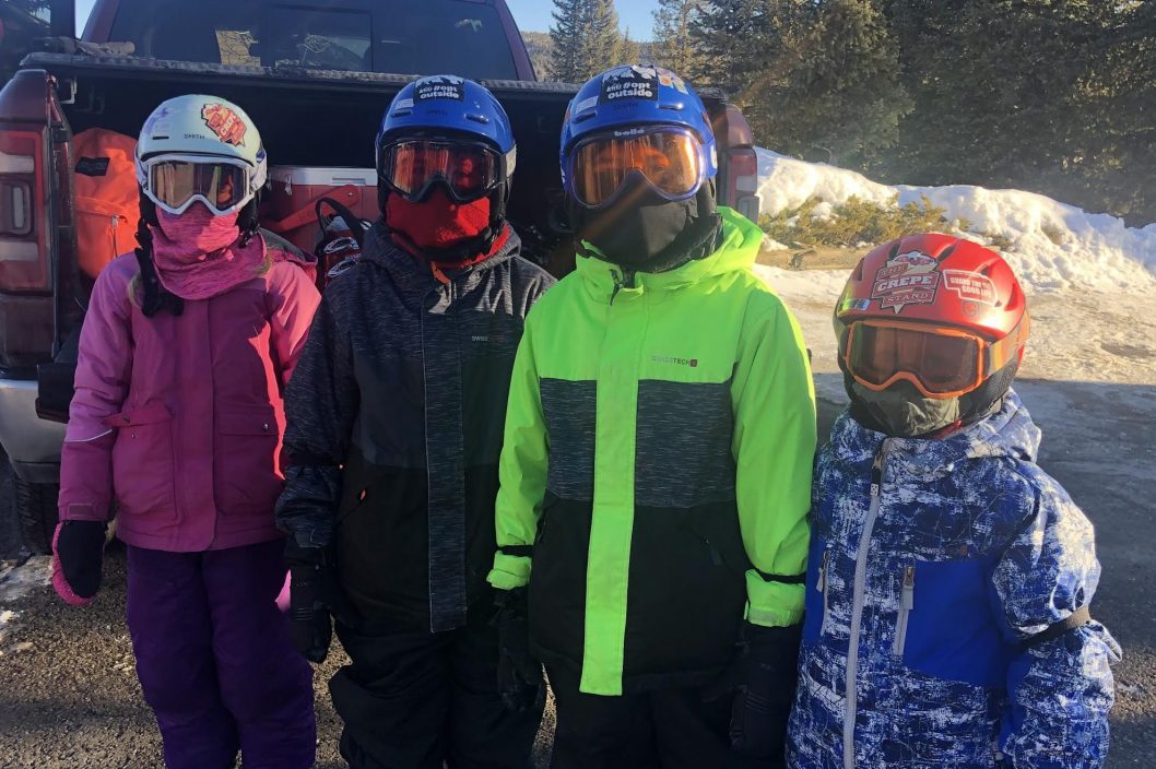 four kids standing in ski gear