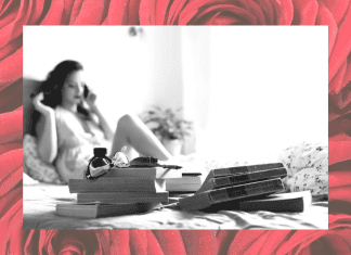 black and white photo of woman on bed in boudoir shoot with red rose background