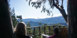 No PCS: The Gift of Staying Put mom holding little girl's hand in porch chairs on a deck overlooking mountains