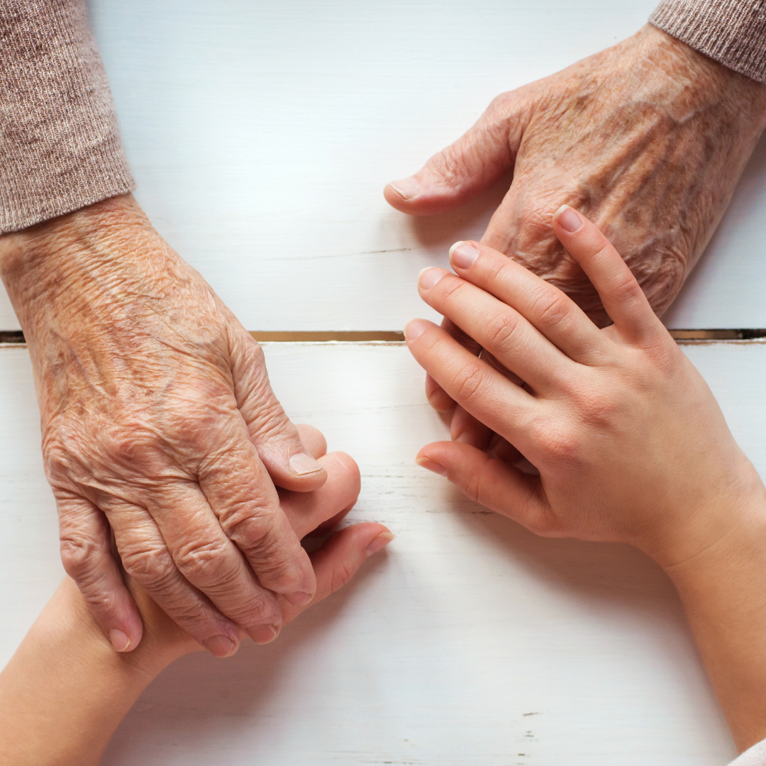 older and younger hands together on table