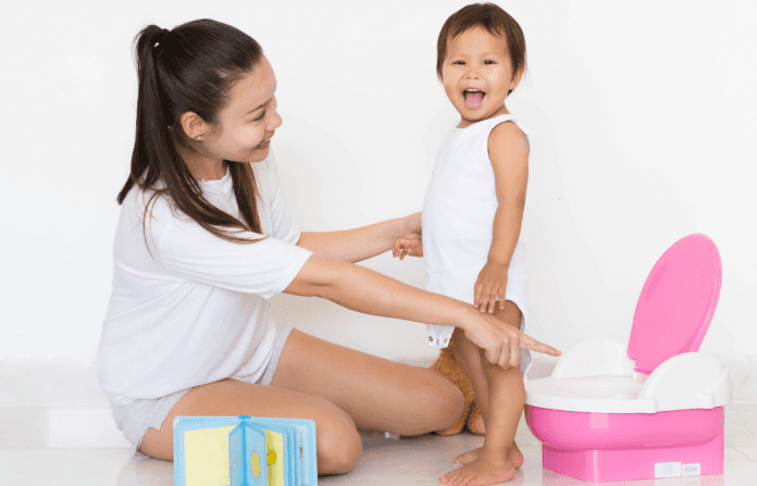 mom and toddler standing with a potty chair