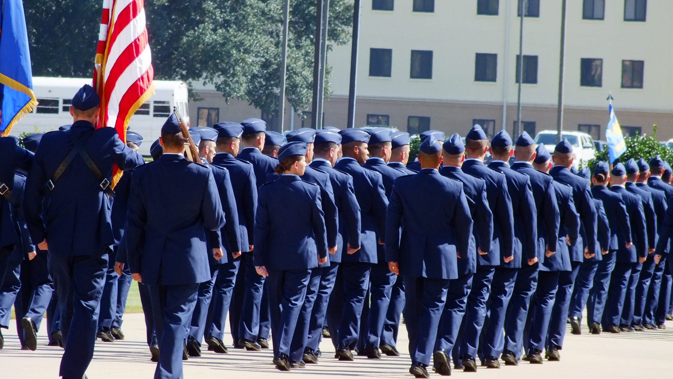 air force military airmen in blues marching with American flag