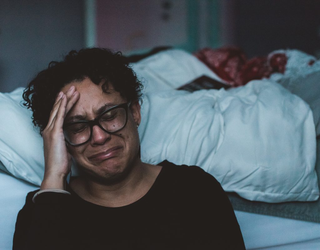 woman crying next to a bed in grief