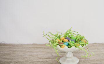 Easter Basket Ideas for Special Needs Kids white platter with Easter grass and eggs on wood table