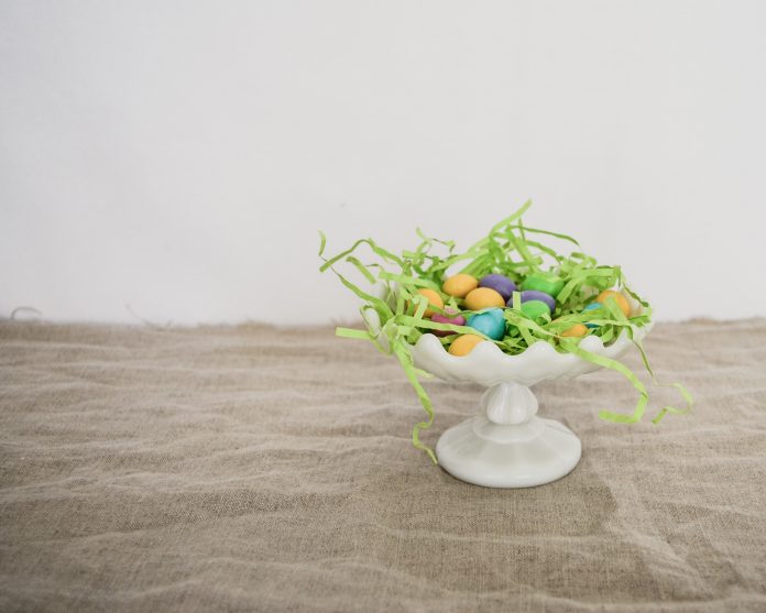 white platter with Easter grass and eggs on wood table