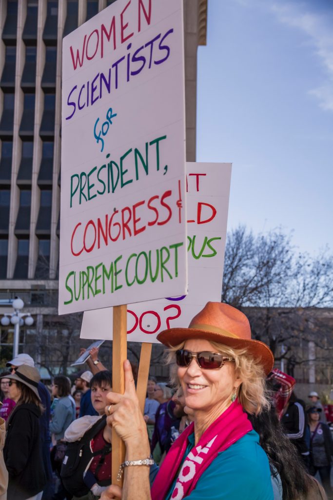 woman in a march holding up a sign that states, "women scientists for president, congress, supreme court"