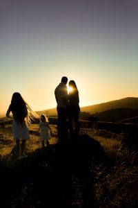 a family in a field backlit by the setting sun