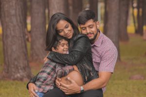 a son and father embracing a mother and her pregnant belly